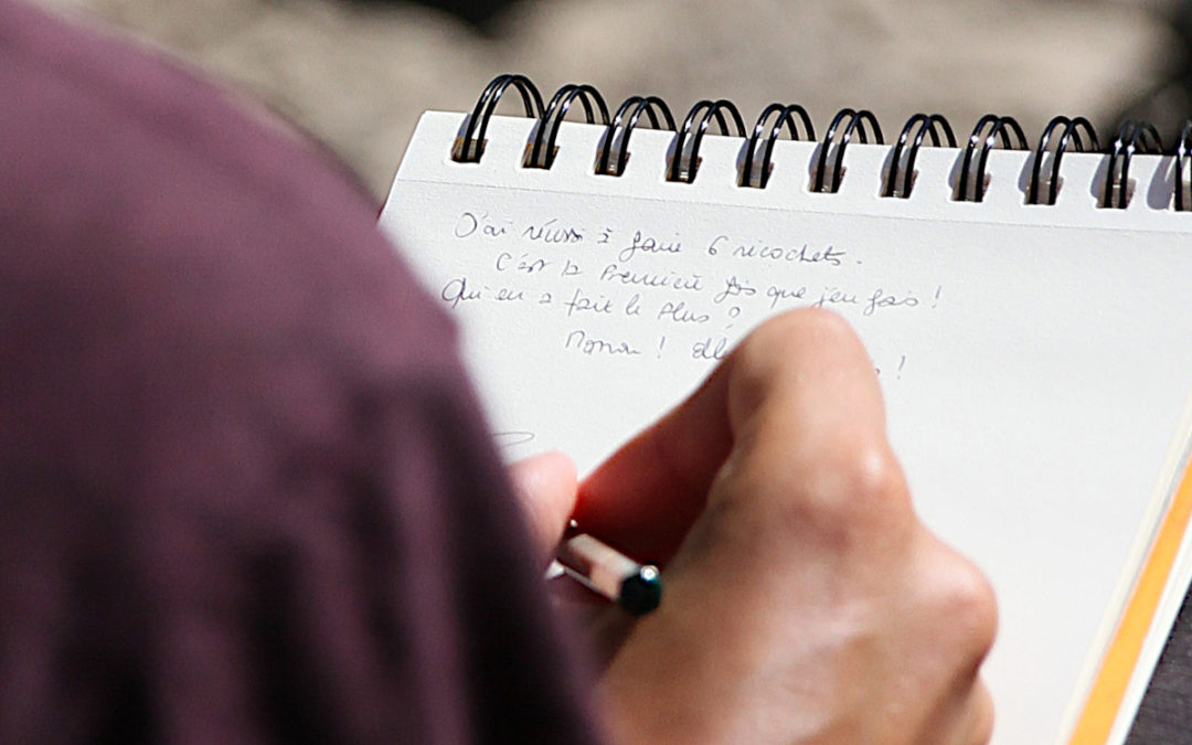 Une main qui dessine et qui écrit les dialogues d'un groupe de jeunes en séjour dans le massif des Ecrins proche de Grenoble